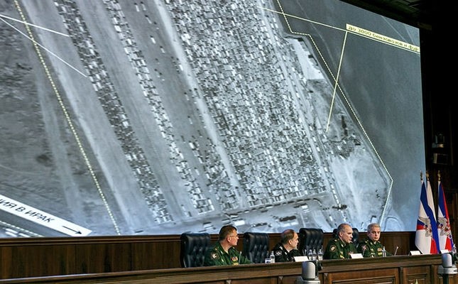Russian top military officials speak to the media in front of an aerial image which they say is oil trucks near Turkeyu2019s border with Syria is displayed by the Russian Defense Ministry at a briefing in Moscow, Dec. 2, 2015. (AP Photo)