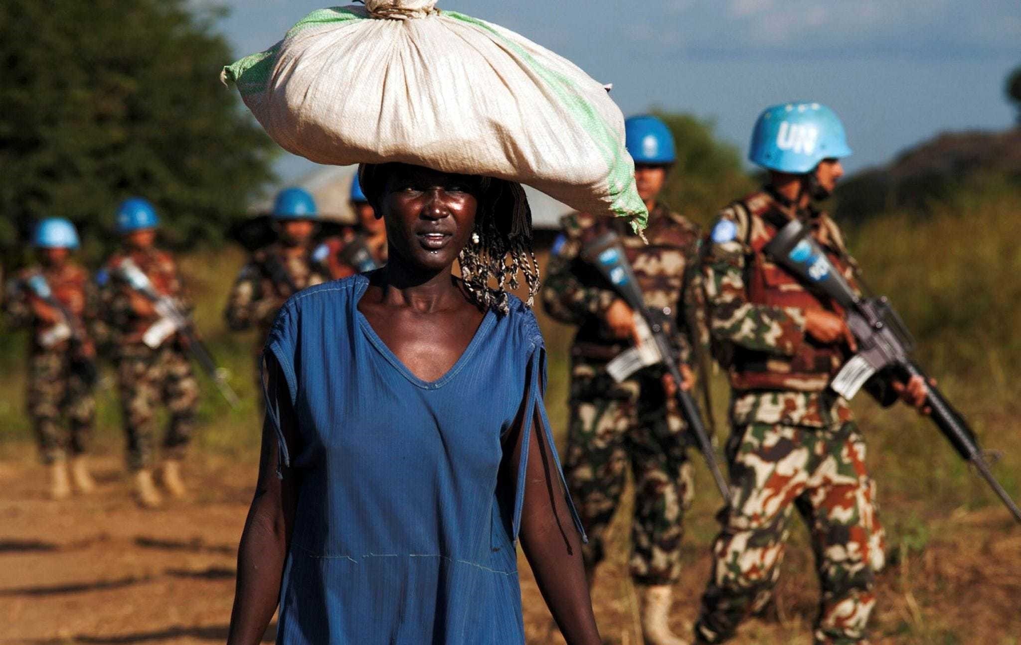 A displaced woman carrying goods as United Nations Mission in South Sudan (UNMISS) peacekeepers patrol outside the premises of the UN Protection of Civilians (PoC) site in Juba.
