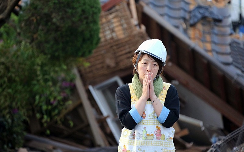 In this Saturday, April 16, 2016, file photo, a resident stands in front of damaged house in Mashiki, Kumamoto prefecture, Japan (AP Photo)