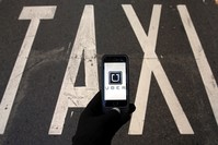 The logo of car-sharing service app Uber on a smartphone over a reserved lane for taxis in a street is seen in this photo illustration taken in Madrid on December 10, 2014 (Reuters Photo)