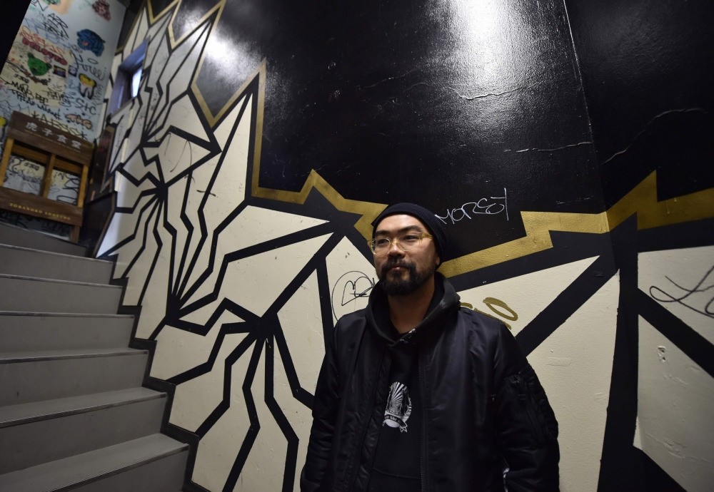  Japanese street artist Kohei Yamao, better known by his nom d'artiste BAKIBAKI, poses with his work in Tokyo. 