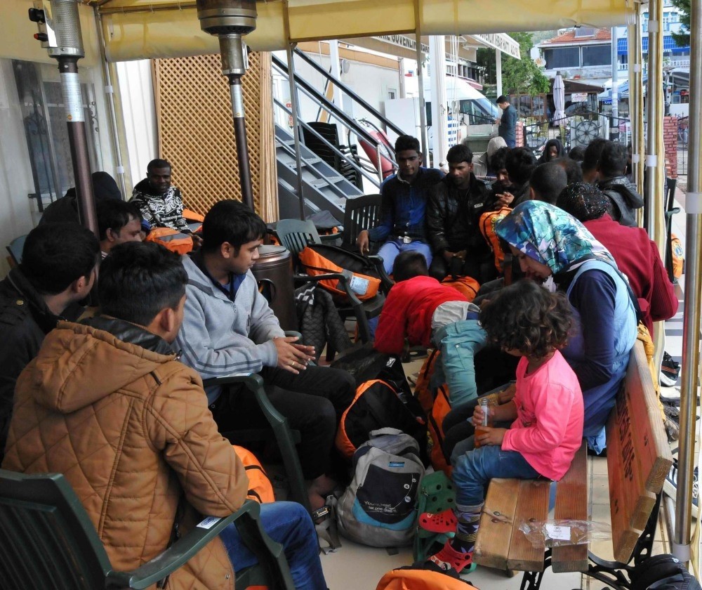 Migrants sit outside a Coast Guard station in Ayvacu0131k, u00c7anakkale, after they were brought to the port 