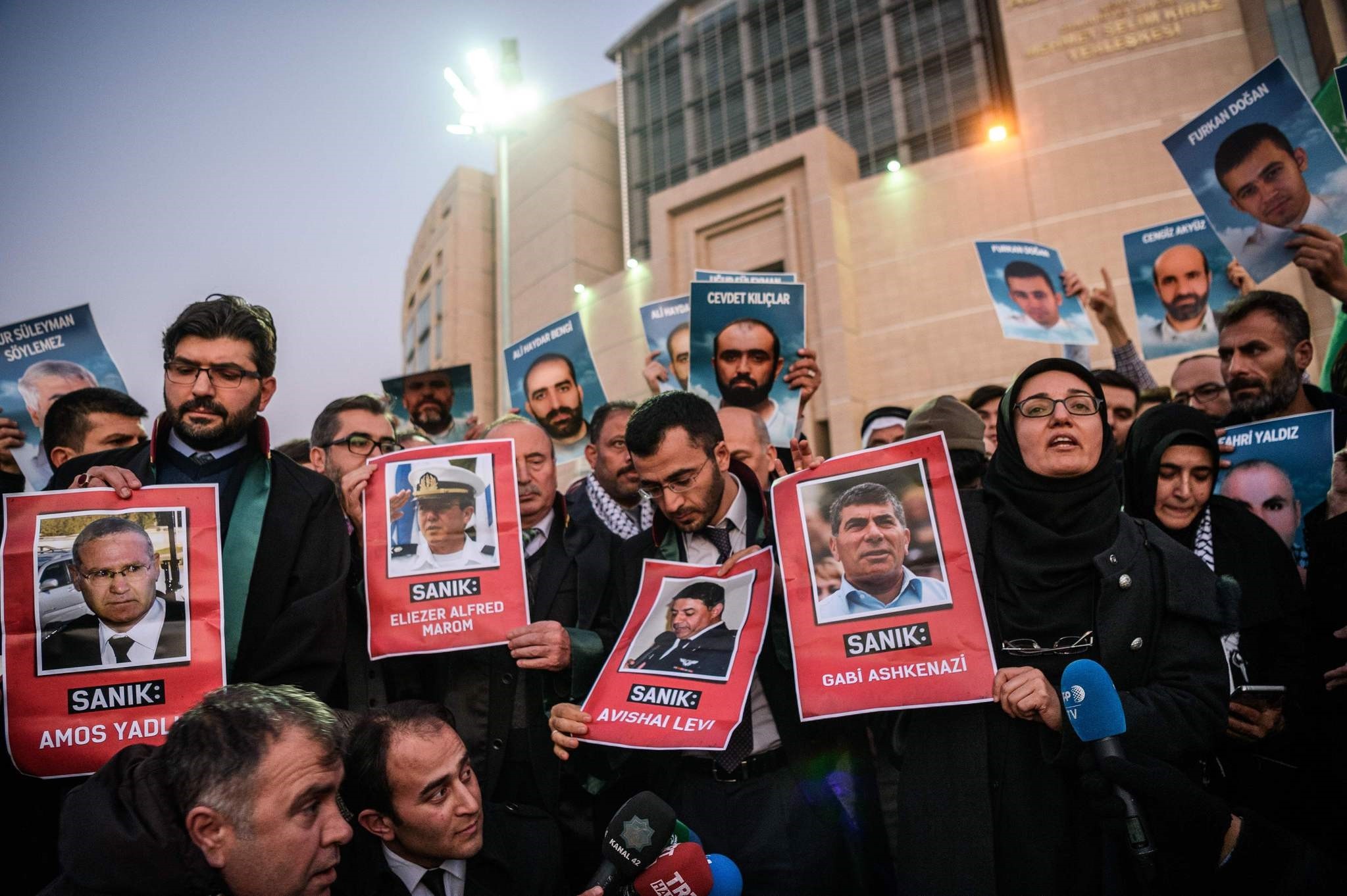 Lawyers hold pictures of accused ex-Israeli army officers as families (back) hold pictures of victims on December 9, 2016 outside the Istanbul courthouse. (AFP Photo)