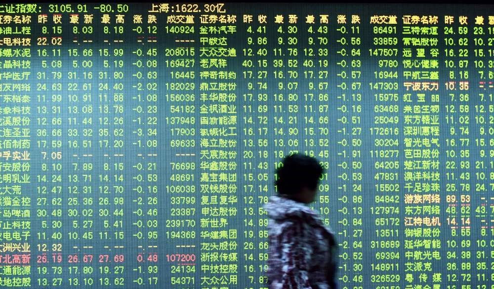An investor walks past a screen showing stock market movements at a securities firm in Hangzhou in eastern Chinau2019s Zhejiang province.