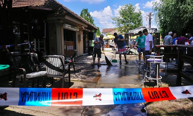  People clean up the ground behind a police ruban at a cafe after a man shot dead five people in the village of Zitiste, northern Serbia on July 2, 2016 (AFP Photo)