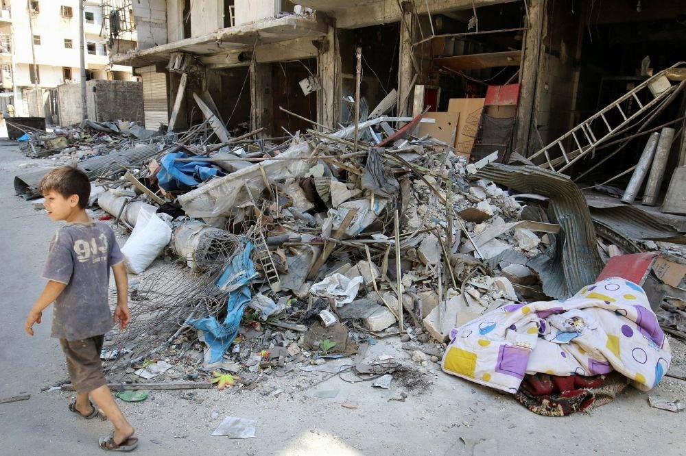 A boy walks past damaged shops in the opposition-held part of Aleppo, frequently targeted by Russia.