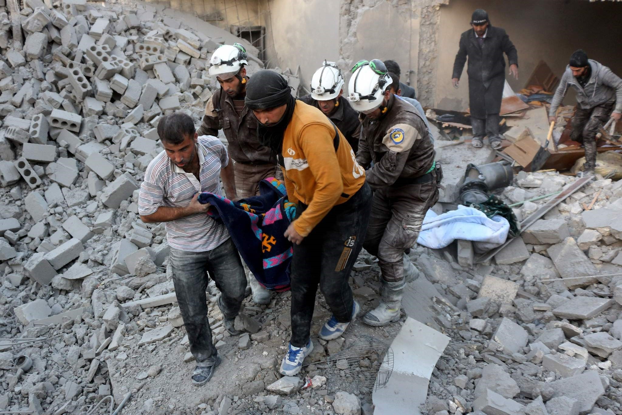 Syrian civil defence volunteers evacuate a victim from the rubble of a building following reported airstrikes on Aleppo's rebel-held district of al-Hamra on November 20, 2016. (AFP PHOTO)