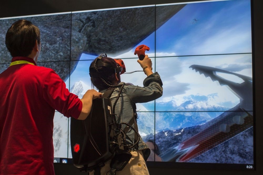 A woman climbs a mountain in a VR experience at the Tsinghua Tongfang exhibit booth during the 2017 Consumer Electronic Show (CES) in Las Vegas.