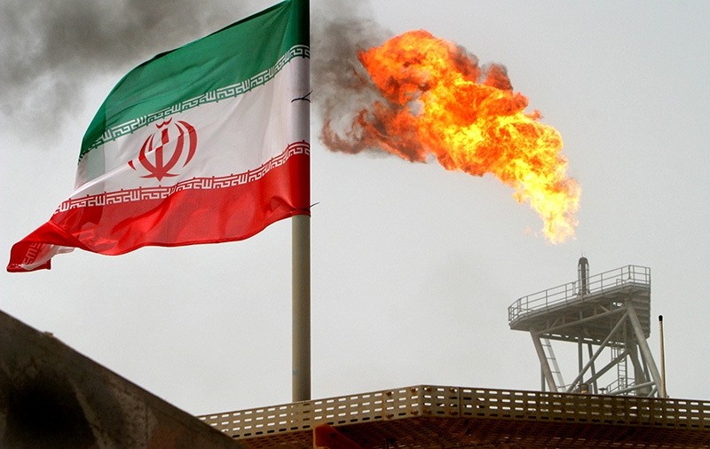 A gas flare on an oil production platform in the Soroush oil fields is seen alongside an Iranian flag in the Persian Gulf, Iran, July 25, 2005. (Reuters Photo)
