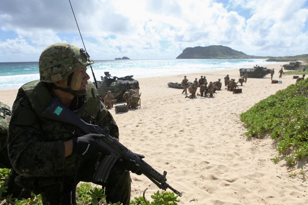 A soldier with the Japan Maritime Self-Defense Force sets up a perimeter defense during a simulated beach assault at Marine Corps Base Hawaii during the multi-national military exercise RIMPAC in Kaneohe, Hawaii.