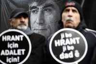 Activists hold placards reading ,For Hrant, For Justice, against the backdrop of a large poster of the slain journalist during a commemoration ceremony in January 2016 in Istanbul.