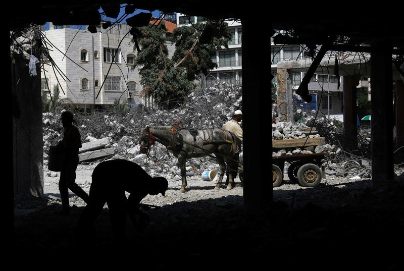 Palestinian workers remove debris from buildings which were destroyed during the 50-day war between Israel and Hamas militants in the summer of 2014, in Gaza City, on August 10, 2016.  AFP Photo