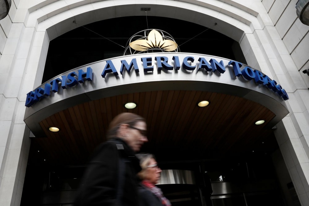 People walk past the British American Tobacco offices in London.