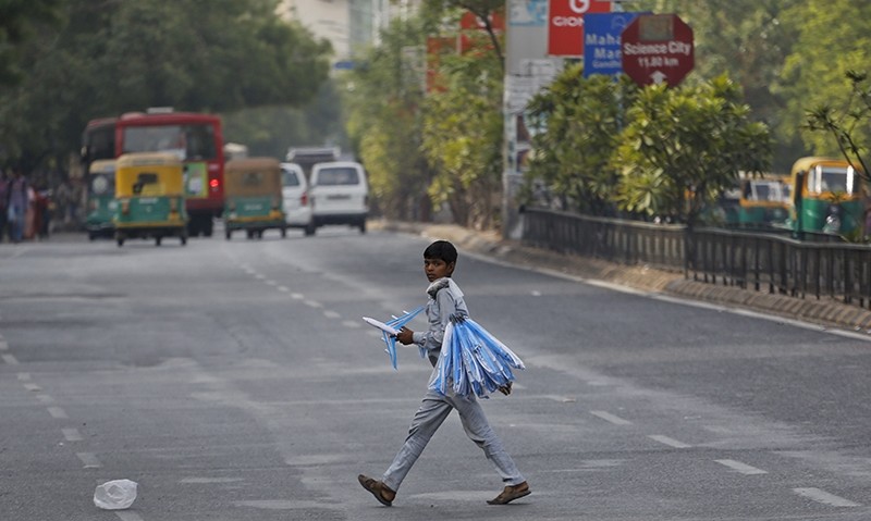 An Indian boy who sells toy planes at a traffic intersection reacts to camera as he crosses a road on the eve of World Day Against Child Labor in Ahmadabad (AP Photo)