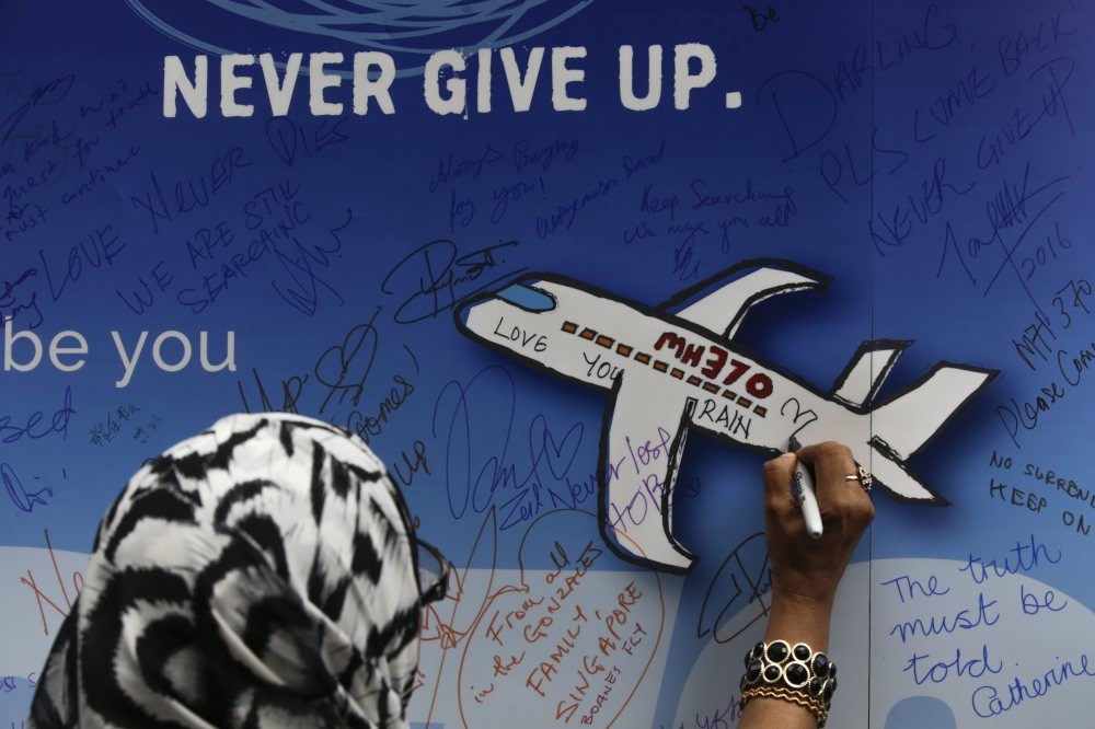 A file picture dated 06 March 2016 shows a woman writing messages for passengers of missing Malaysia Airlines flight MH370 on a banner during a remembrance ceremony to mark the second anniversary of plane's disappearance, in Kuala Lumpur, Malaysia.