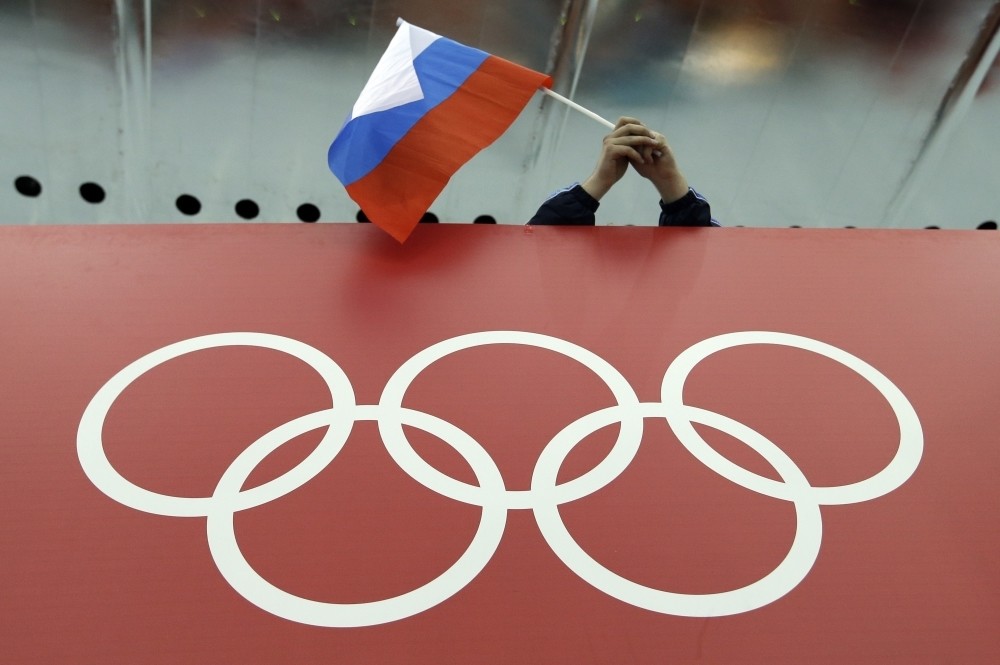 A Russian skating fan holds the countryu2019s national flag over the Olympic rings before the start of the menu2019s 10,000-meter speedskating race during the 2014 Winter Olympics in Sochi, Russia.