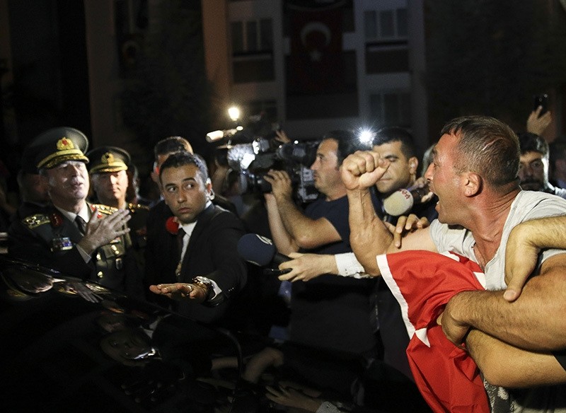 A citizen holding a magazine and a Turkish flag protests Gu00fclenist terror-cult leader Fetullah Gu00fclen as Chief of Staff Akar getting ready to leave in with his car, in Ankara, on August 9. (AA Photo)