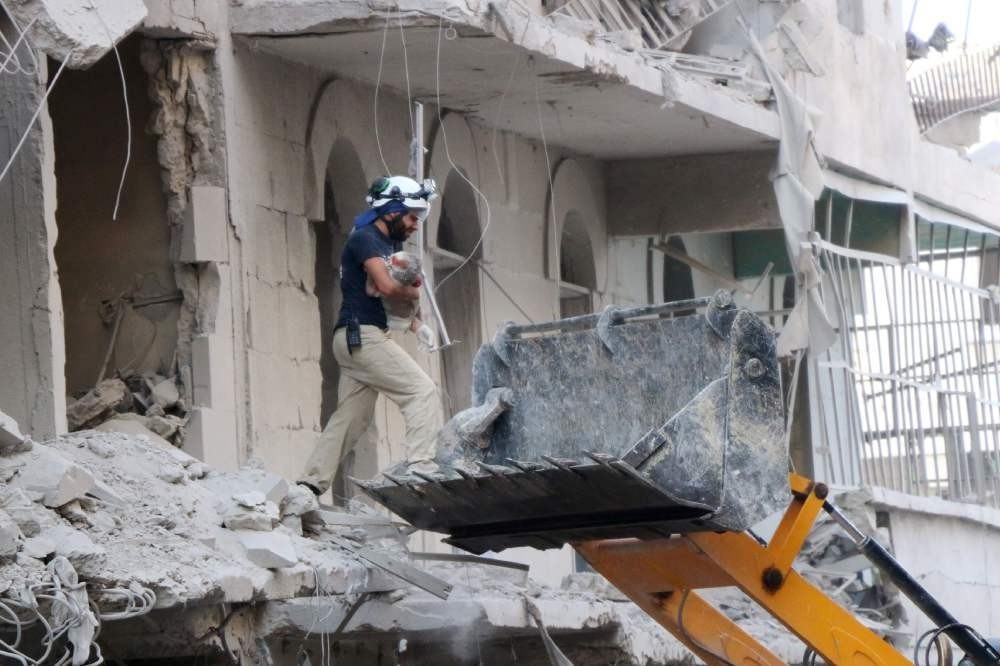 A Syrian rescue worker removes the body of an infant from the rubble of a damaged building following reported Assad regime air strikes on July 7.
