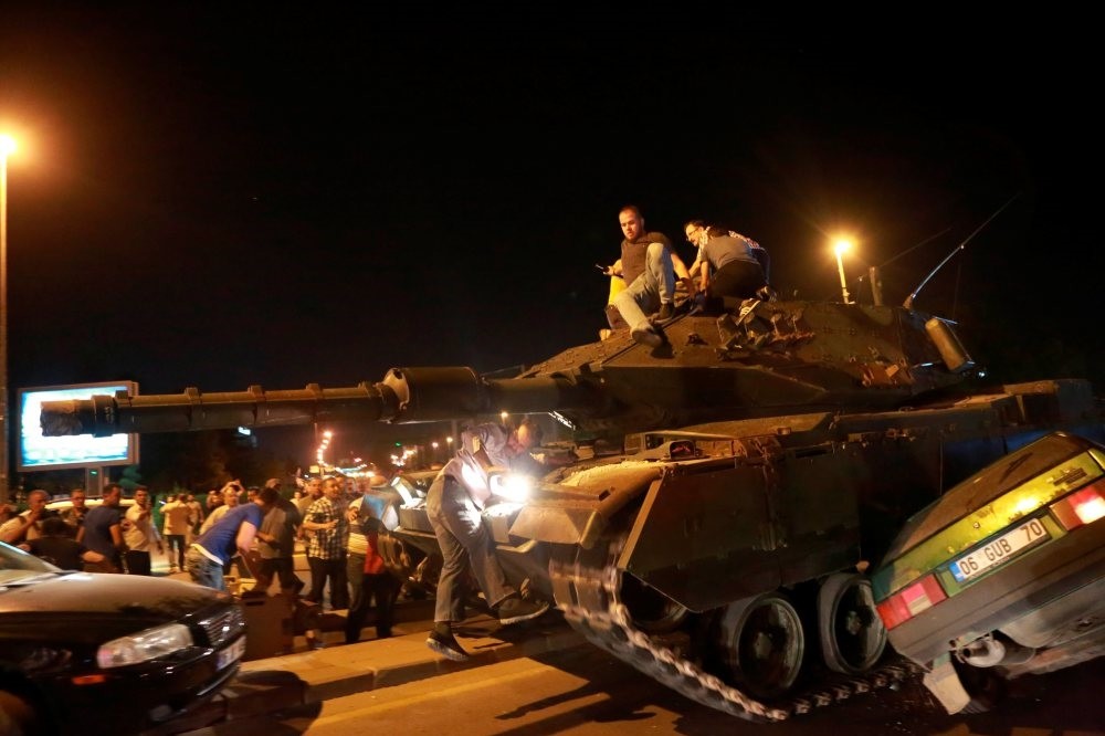 People take over a tank as it crashes into a car during the coup attempt in Ankara on July 15, 2016.