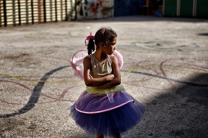 A young girl stands in the courtyard of an abandoned school used by volunteers for hosting Syrian and Afghan refugees in Athens on July 1, 2016. (AFP Photo)