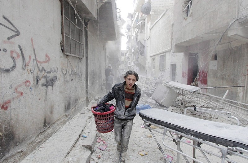 A boy carries his belongings at a site hit by a barrel bomb dropped by  Syria's Bashar Assad forces in Aleppo's al-Fardous district, Syria April 2, 2015. (Reuters Photo)