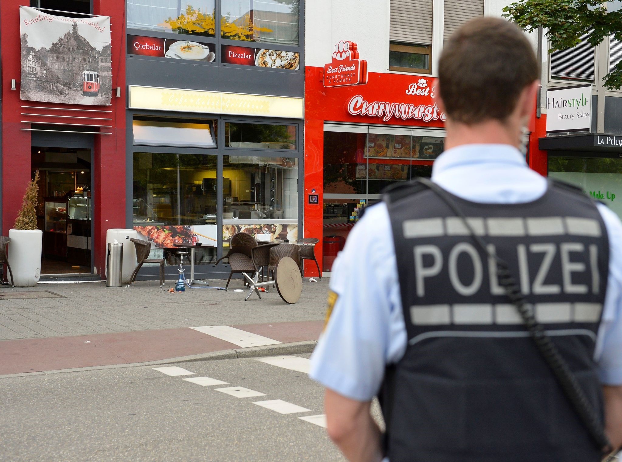 A police officer stands in front of a fastfood restaurant in Reutlingen, southwestern Germany, on July 24, 2016 where a Syrian asylum-seeker killed a woman and injured two people with a machete. (AFP Photo)
