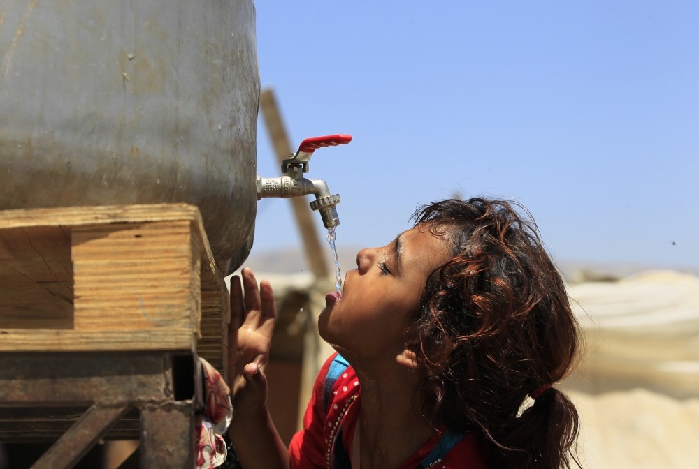 Syrian refugee Amani al-Antar, 7, who fled with her family from the city of Deir al-Zour, Syria, drinking water at a Syrian refugee camp in the eastern Lebanese town of Saadnayel, Bekaa Valley.