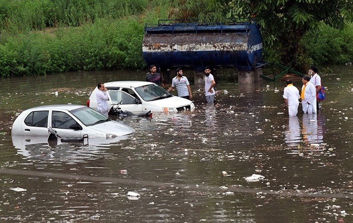 Indian people stands with their drowned vehicles at parking of Maulana Azad Stadium after a heavy monsoon shower in Jammu, the winter capital of Kashmir, India, 21 June 2016. (EPA Photo)