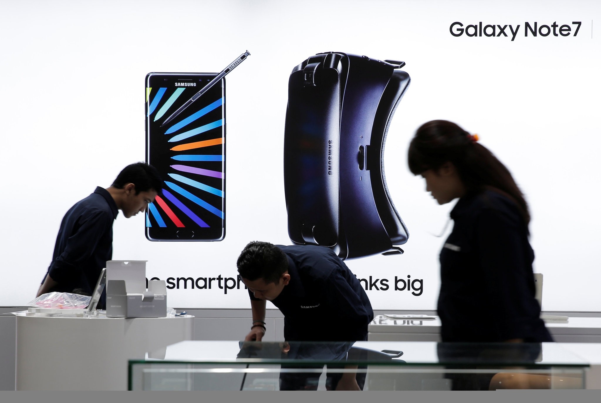 Sales promotion staff stand in front of a Galaxy Note 7 advertisement at a Samsung store in Jakarta, Indonesia.