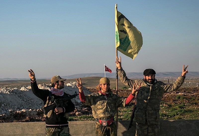 In this Feb. 22, 2015 file photo, YPG terrorists make a V-sign next to a drawing of Abdullah u00d6calan, jailed PKK leader, in Esme village in Aleppo province, Syria. (AP Photo)