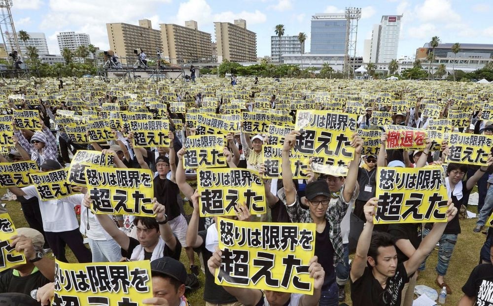 Protesters hold placards that read: ,Our anger has reached its limit, during a protest rally against the presence of U.S. military bases.