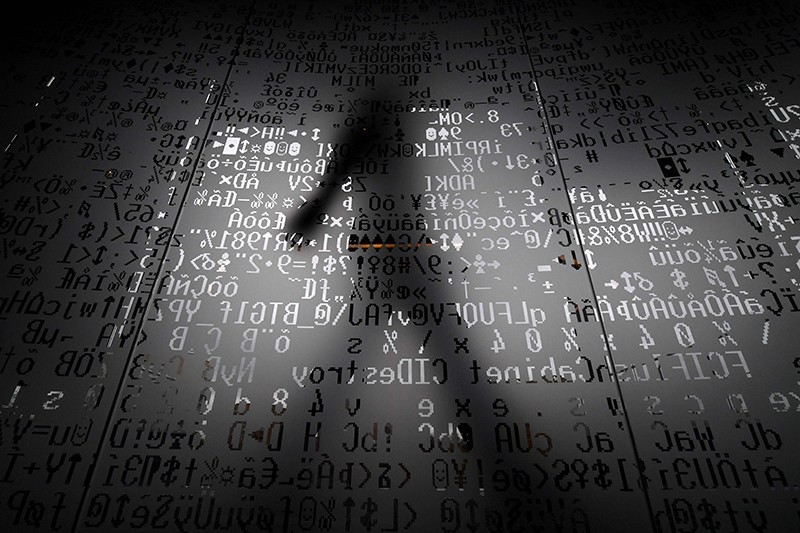 A picture taken on October 17, 2016 shows an employee walking behind a glass wall with machine coding symbols at the headquarters of Internet security giant Kaspersky in Moscow. (AFP Photo)