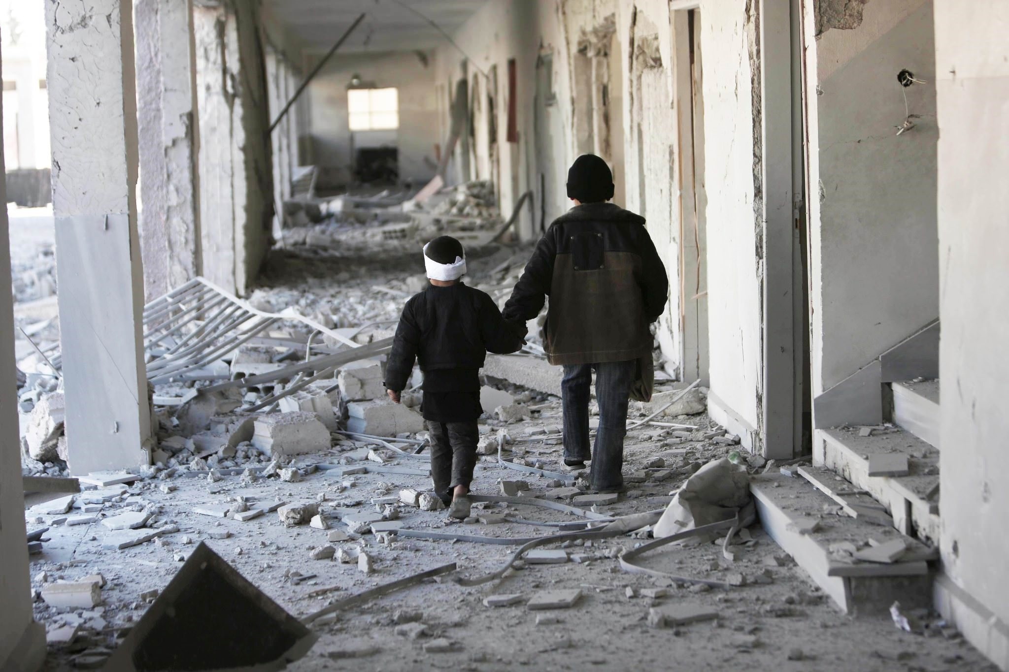 In this Nov. 25, 2015 photo provided by Save the Children, two children walk through the corridors of a destroyed school in Eastern Ghouta, Syria. (Photo by Save the Children via AP)