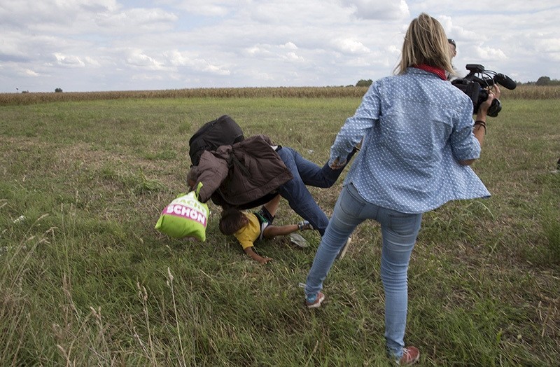 A refugee carrying a child falls after tripping on TV camerawoman (R) Petra Laszlo while trying to escape from a collection point in Roszke village (Reuters Photo)
