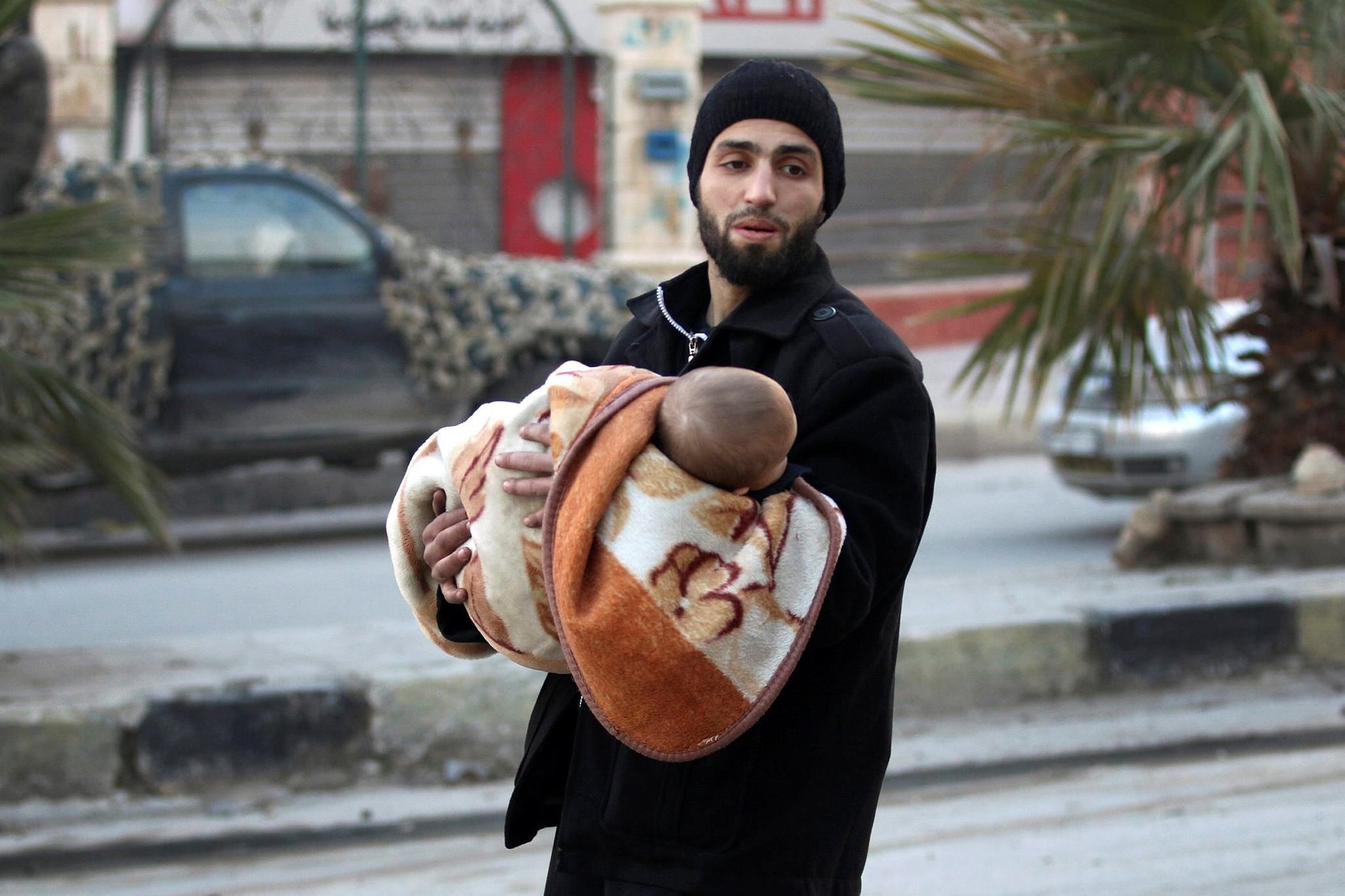 A man carries a child as he flees deeper into the remaining opposition-held areas of Aleppo, Syria, Dec. 12.