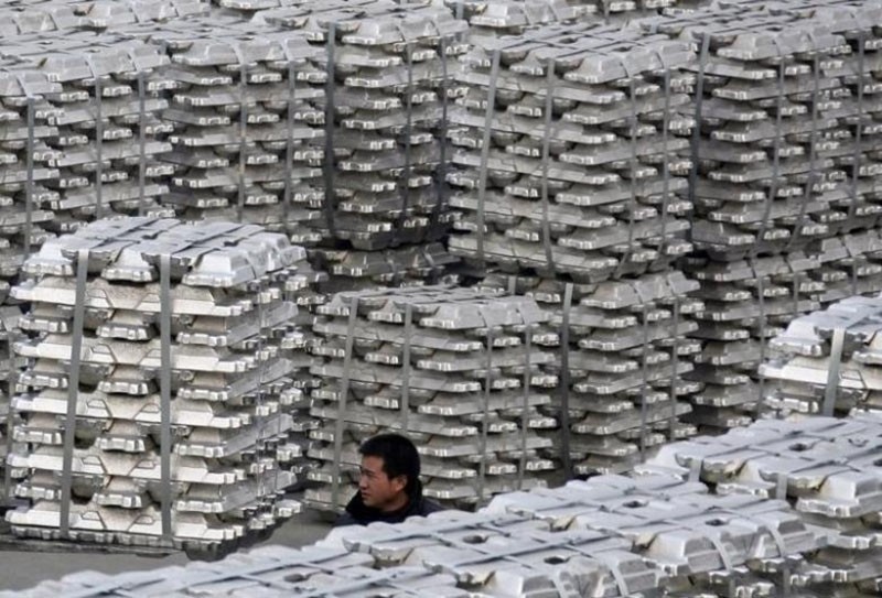 A worker walks among piles of aluminium ingots at a storage of aluminium plant in Yuncheng, Shanxi province January 7, 2010. (Reuters Photo)