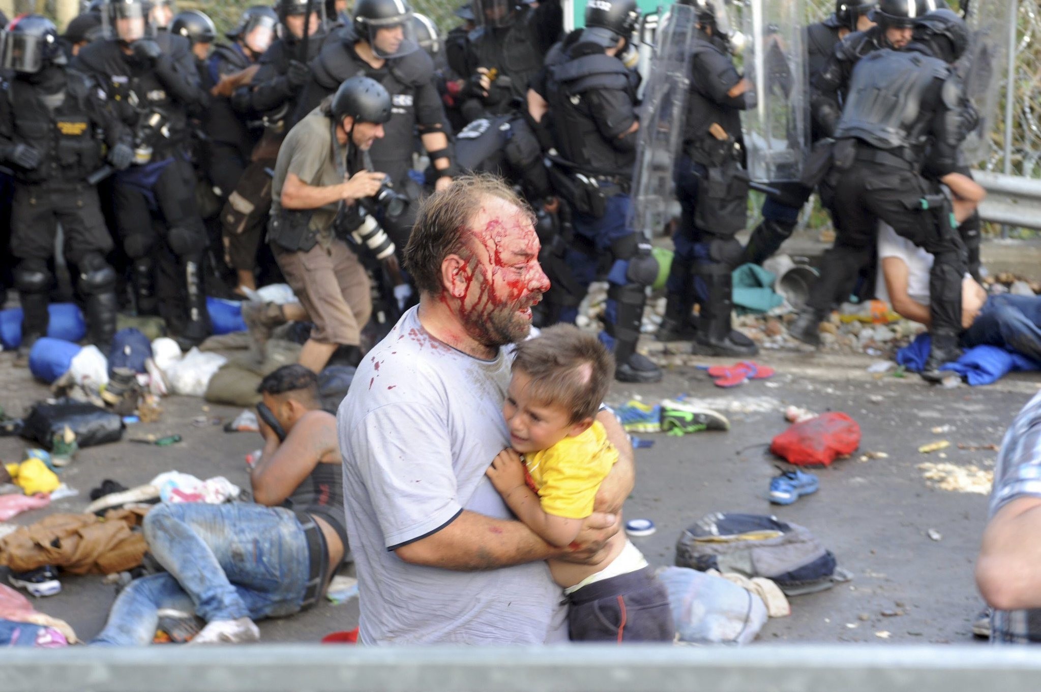 An injured migrant carries a child during clashes with Hungarian riot police at the border crossing with Serbia in Roszke, Hungary September 16, 2015. (Reuters Photo)