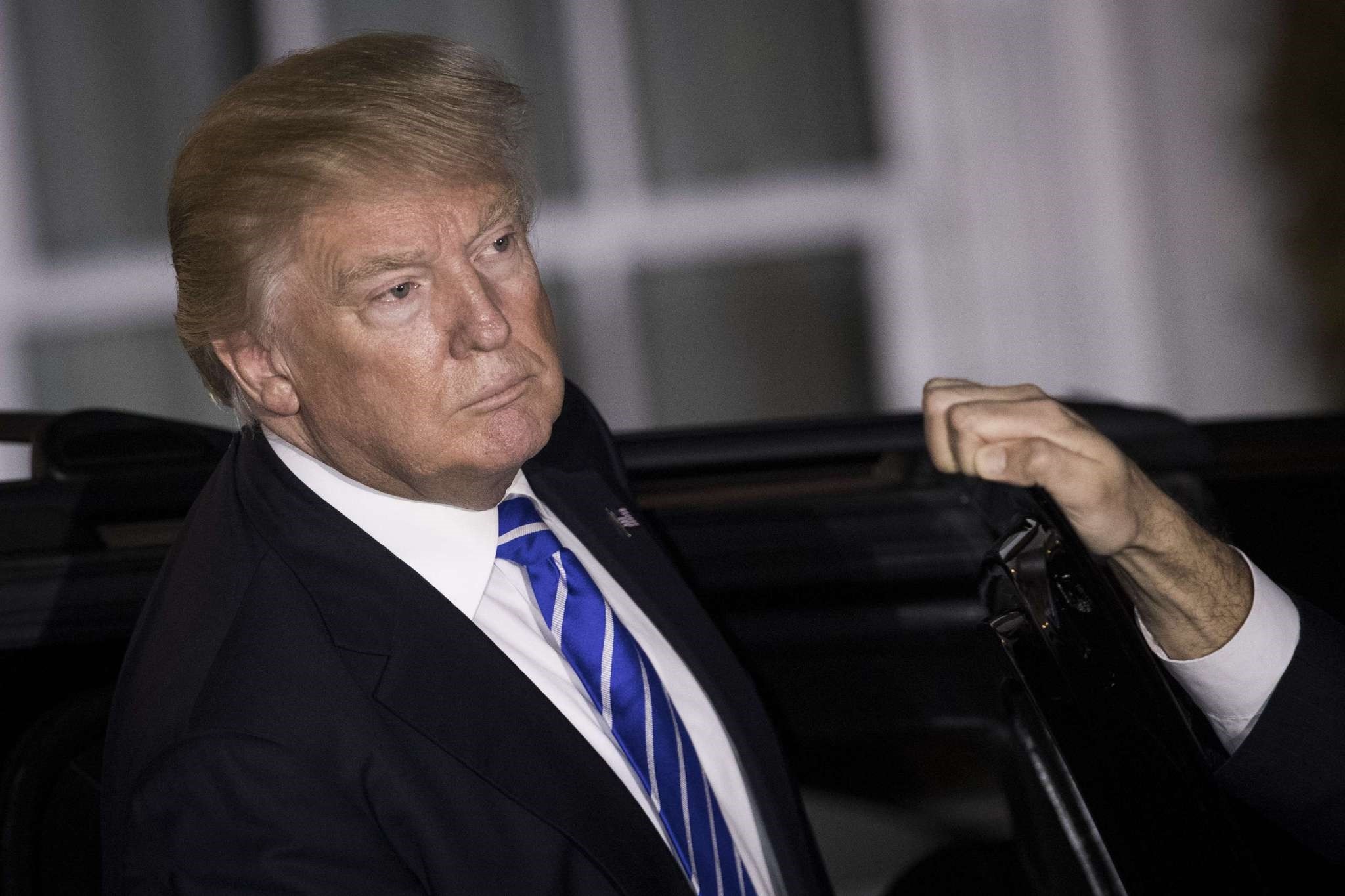 The photograph shows Trump listening to questions from the press as he gets into his car after a day of meetings at Trump International Golf Club, Nov. 19, 2016, Bedminster Township, New Jersey.