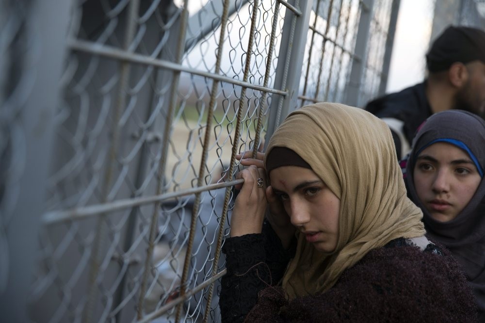 A young Syrian woman leans on the metal fence separating them from Macedonia at the Greek border station of Idomeni, Feb. 28. (AP Photo)