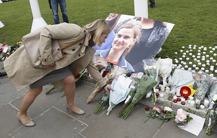 A woman leaves a floral tribute next to a photograph of murdered Labour Member of Parliament Jo Cox in Parliament Square, London, Britain June 17, 2016 (Reuters Photo)