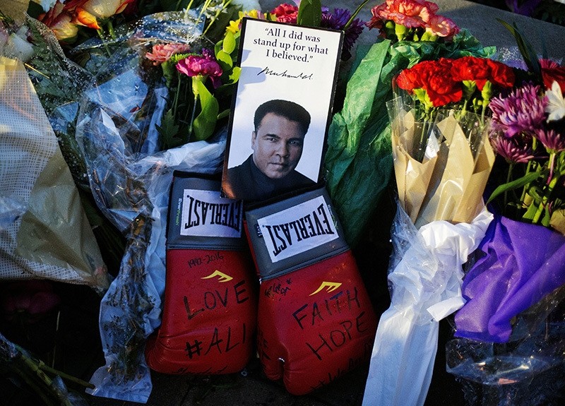 Boxing gloves and a message sit among flowers at a makeshift memorial to Muhammad Ali at the Muhammad Ali Center, Saturday, June 4, 2016, in Louisville, Ky. Muhammad Ali died Friday at age 74. (AP Photo)