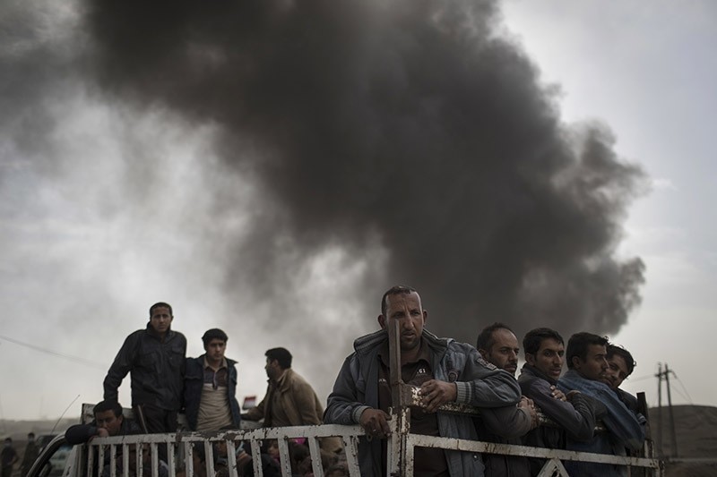 Displaced people stand on the back of a truck at a checkpoint near Qayara, south of Mosul. (Photo AP)