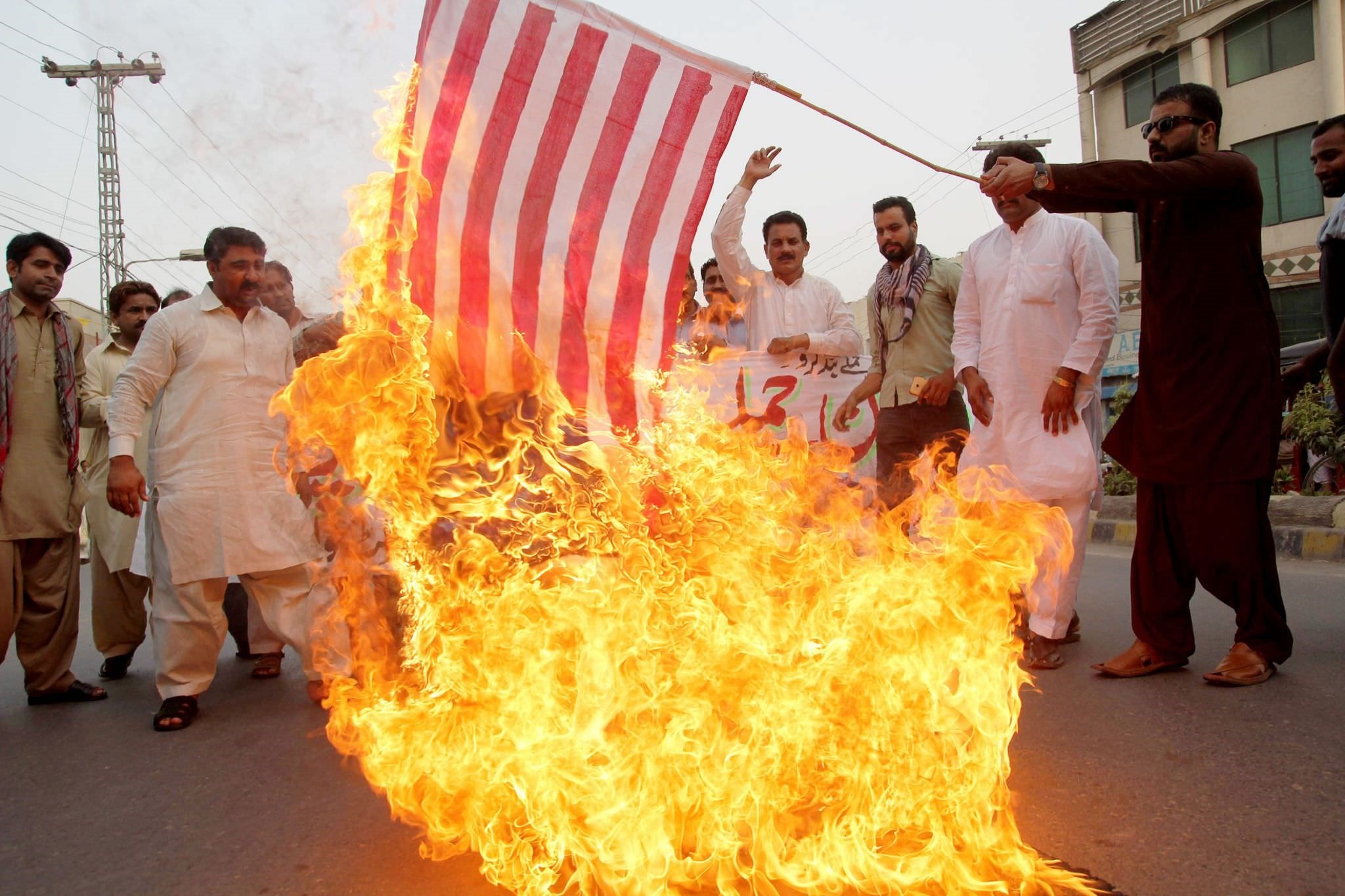 A Pakistani demonstrator holds a burning US flag as others shout slogans during a protest in Multan on May 24, 2016, against a US drone strike in Pakistan (AFP Photo)