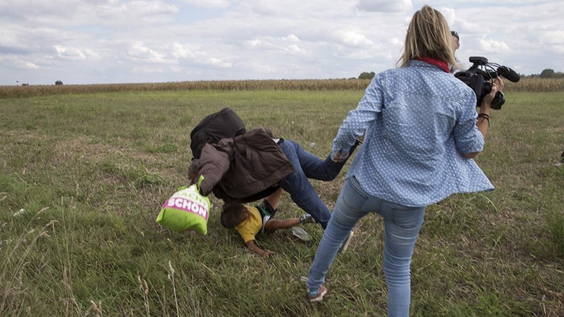 A refugee carrying a child falls after tripping on TV camerawoman (R) Petra Laszlo while trying to escape from a collection point in Roszke village (Reuters Photo)