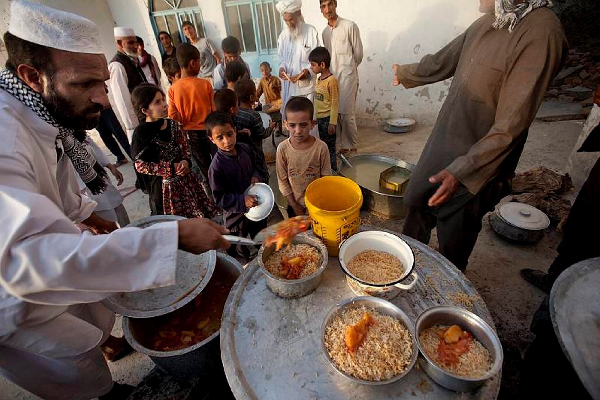 Afghan children stand in a queue as they receive food distributed on the first day of holy month of Ramadan outside a mosque in a poor neighborhood of Kabul, Afghanistan.