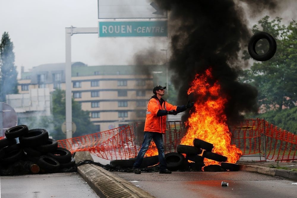 A union member throws a tire onto a pile set ablaze at a blockade onto a main road leading to downtown Rouen, northwestern France, May 31.