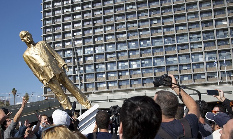 People watch a statue of Israeli Prime Minister Benjamin Netanyahu as it falls at Rabin square in Tel Aviv, Tuesday, Dec. 6, 2016 (AP Photo)