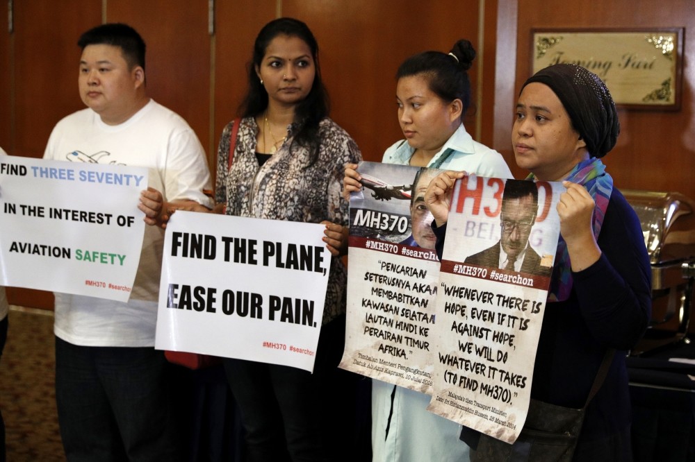 Family members of passengers on board the Malaysia Airlines Flight 370 that went missing on March 8, 2014 hold up a placards during a special press conference in Kuala Lumpur, Malaysia, July 21. (AP Photo)