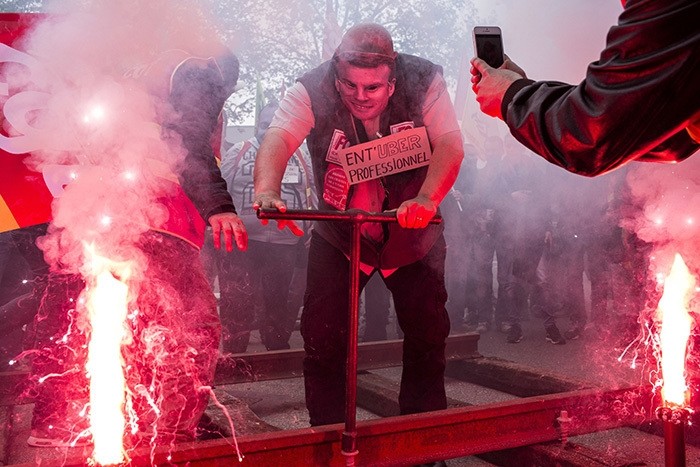 A French rail worker wearing a French Economy Minister Emmanuel Macron mask installs rails during a demonstration in front of the French employers' union MEDEF's branch in Lyon, central France, on Wednesday, June 1, 2016. (AP Photo)