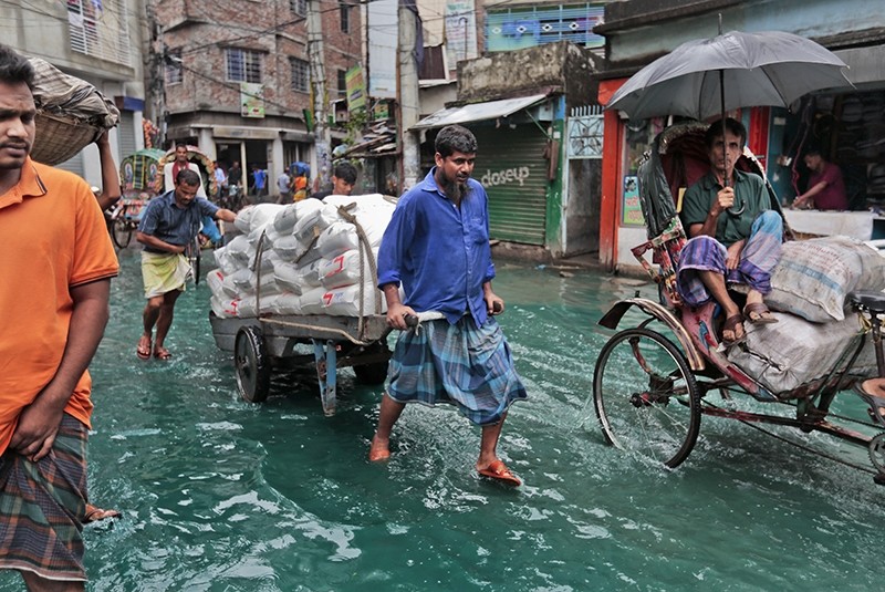 Bangladeshi men pull a loaded cart through a waterlogged street after heavy rainfall in Dhaka, Bangladesh, Saturday, May 21, 2016. (AP Photo)